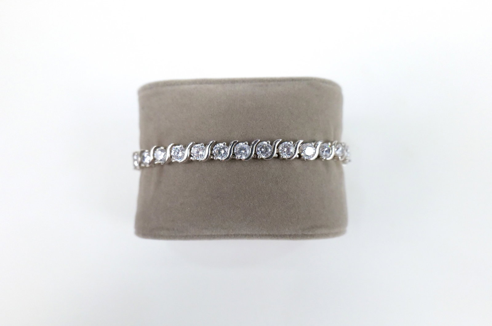 Sterling and CZ Tennis Bracelet: Sterling and CZ Tennis Bracelet. The lot includes a 7 1/4'' long tennis bracelet featuring alternating 4mm round CZ's and "S" shaped links with a tongue closure and double figure 8 safety clasps. Mark
