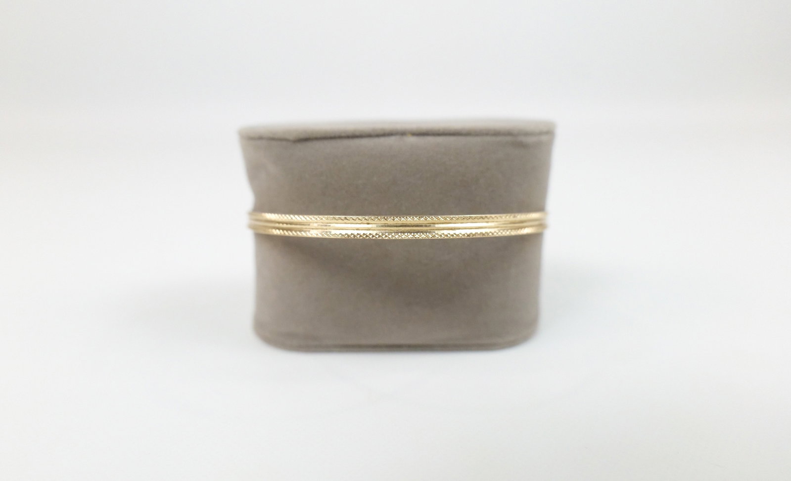 14K Textured Bangle: 14K Textured Bangle. The lot includes a 14K yellow gold bangle with an 8.5'' circumference featuring a channeled center with textured borders. It weighs 6.9 grams and is marked 14K. Used. All invoices