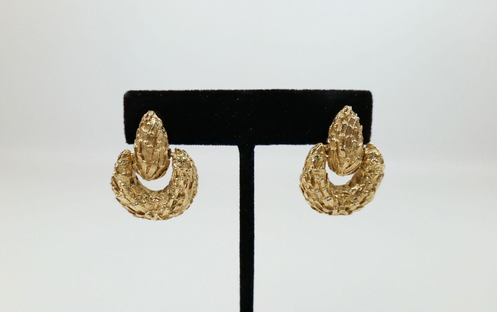 Mid Century 14K Hinged Earrings: Mid Century 14K Hinged Earrings. The lot includes a 1.15'' x .88'' vintage mid century heavy 14K bark textured earrings featuring pear shaped studs with hinged tapered U shaped half hoop bottoms with