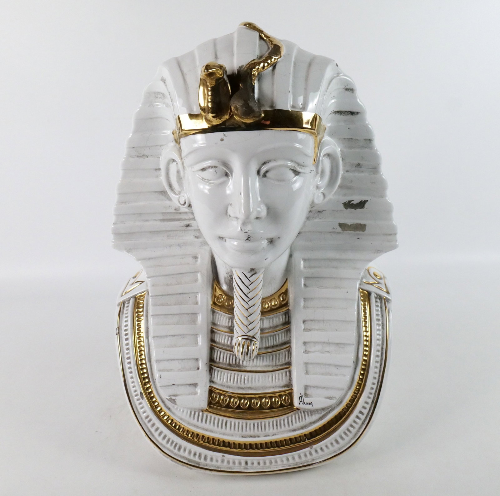 Porcelain Bust of Pharoh: Porcelain Bust of Pharoh. Artist Signed - Aleuea. Has chipping and crazing throughout. Top snake on headdress appears to have been repaired. Measures 19" tall x 13" wide. All invoices must be paid wit