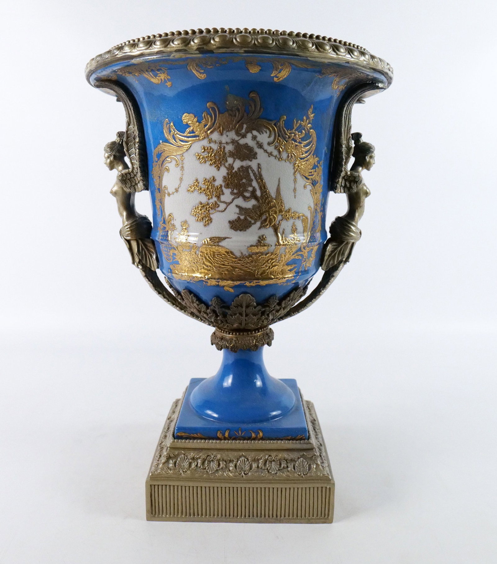 Porcelain and Mixed Metal Urn Vase: Porcelain and Mixed Metal Urn Vase. Has nude angel women handles with hand painted bird decoration with cobalt blue. Late 20th century. Measures 18" tall x 12" diameter. All invoices must be paid with