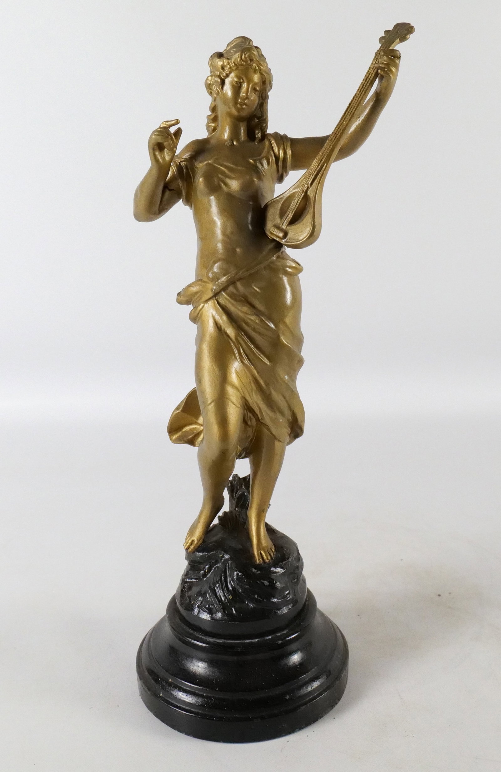 Mixed Metal/Spelter Figurine: Mixed Metal/Spelter Figurine. Depicting a woman playing a guitar. Comes on Cast Iron Base. Plaque on Base states "Pastorale par Aug. Moreau". Right arm has a stress crack - not all the way through. Ea