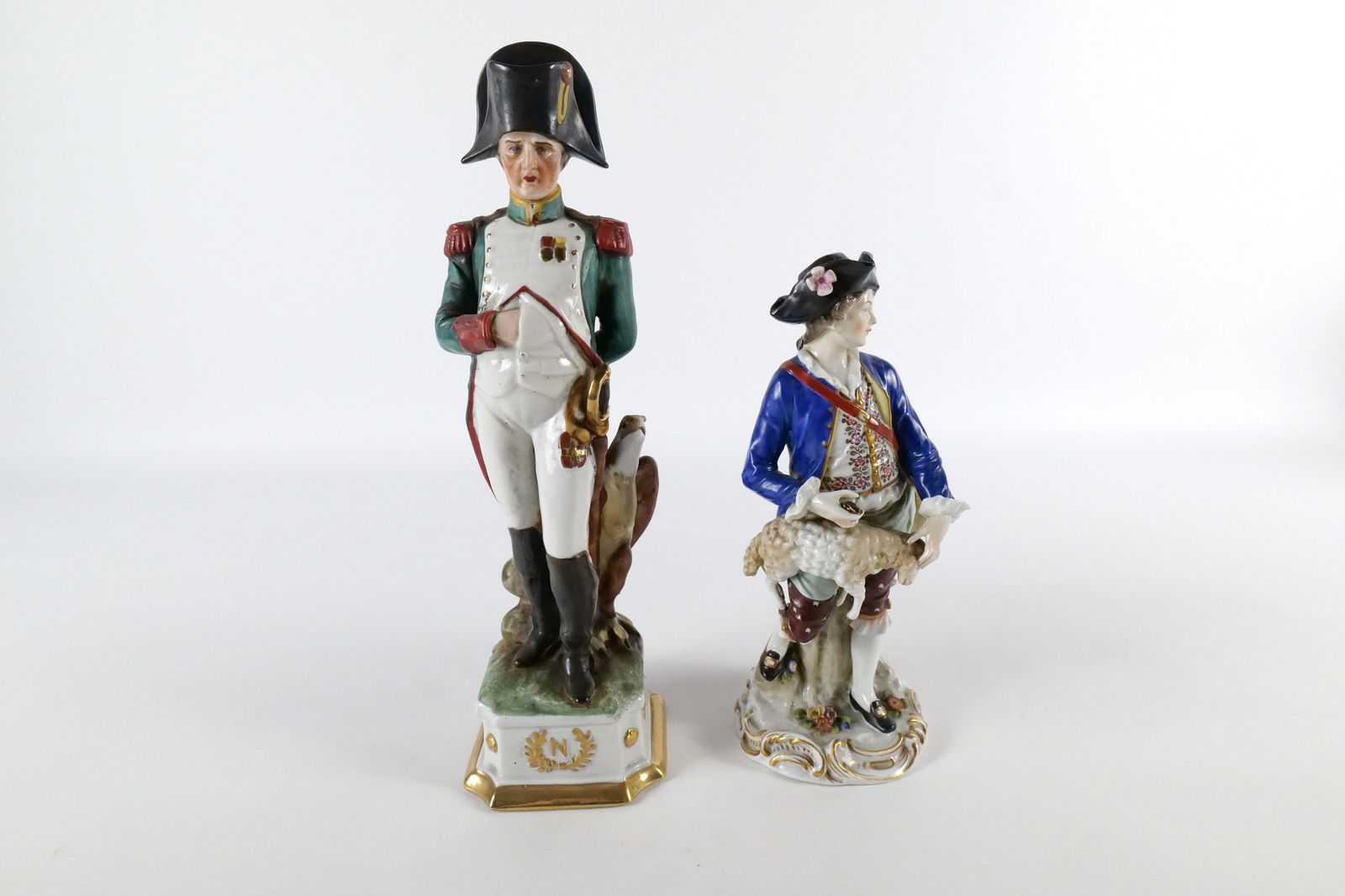 Lot of 2 Hand Painted Porcelain Figurines: Lot of 2 Hand Painted Porcelain Figurines. Including Capodimonte Napolean and 19th Century Shepherd with Goat - Scissors are AS-IS. Largest measures 12" tall. All invoices must be paid within 24 hours