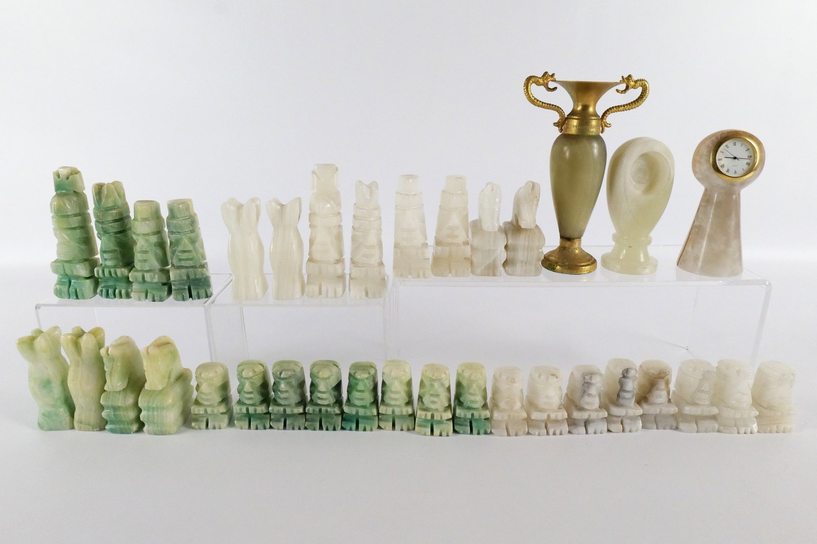 Lot of Carved Stone Pieces: Lot of Carved Stone Pieces. Including Mayan Chess Pieces - Some chips throughout, 2 Clock Holders - One missing a clock, and Bud Vase. All invoices must be paid within 24 hours of the sale. We offer m