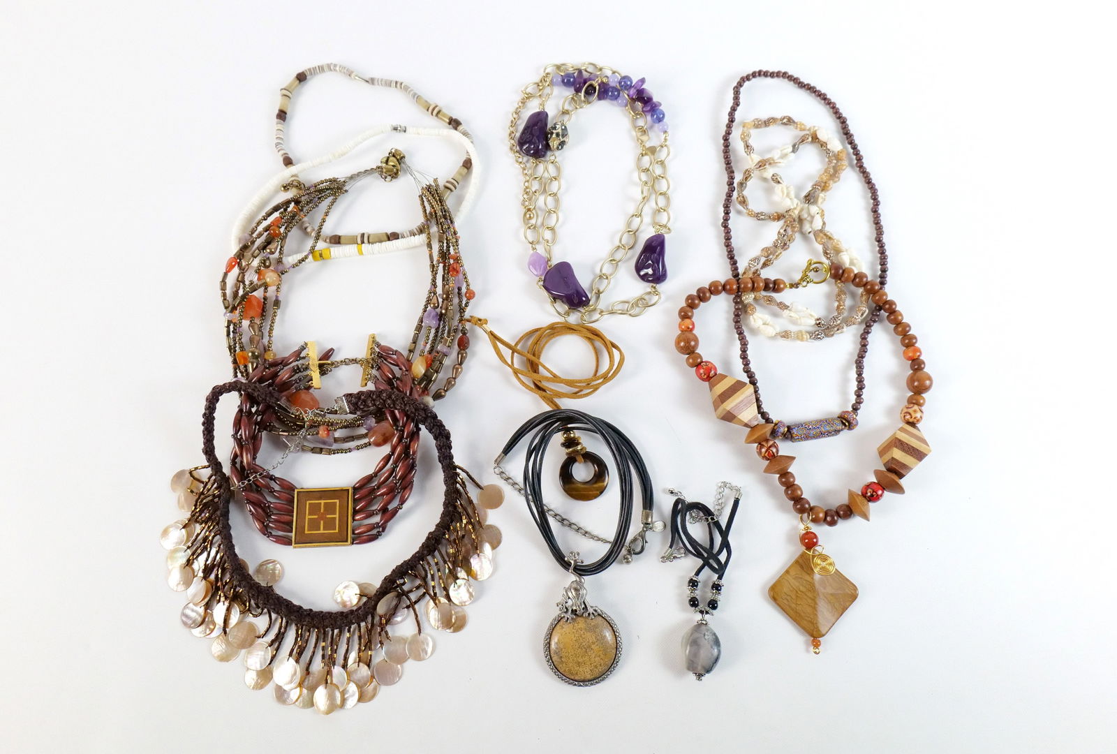 12 Bohemian Costume Necklaces: 12 Bohemian Costume Necklaces. The lot includes a mix of 12 bohemian inspired necklaces. Featuring a 20'' long silver tone and black leather necklace from Chico's with a large silver tone pendant set