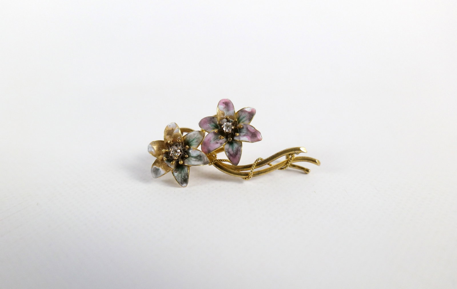 Early 20th Century 18K Flower Brooch: Early 20th Century 18K Flower Brooch. The lot includes an early 20th century 18K yellow gold brooch in the form of a pair of flowers with enameled petals and 2mm round natural diamonds. It measures 1.
