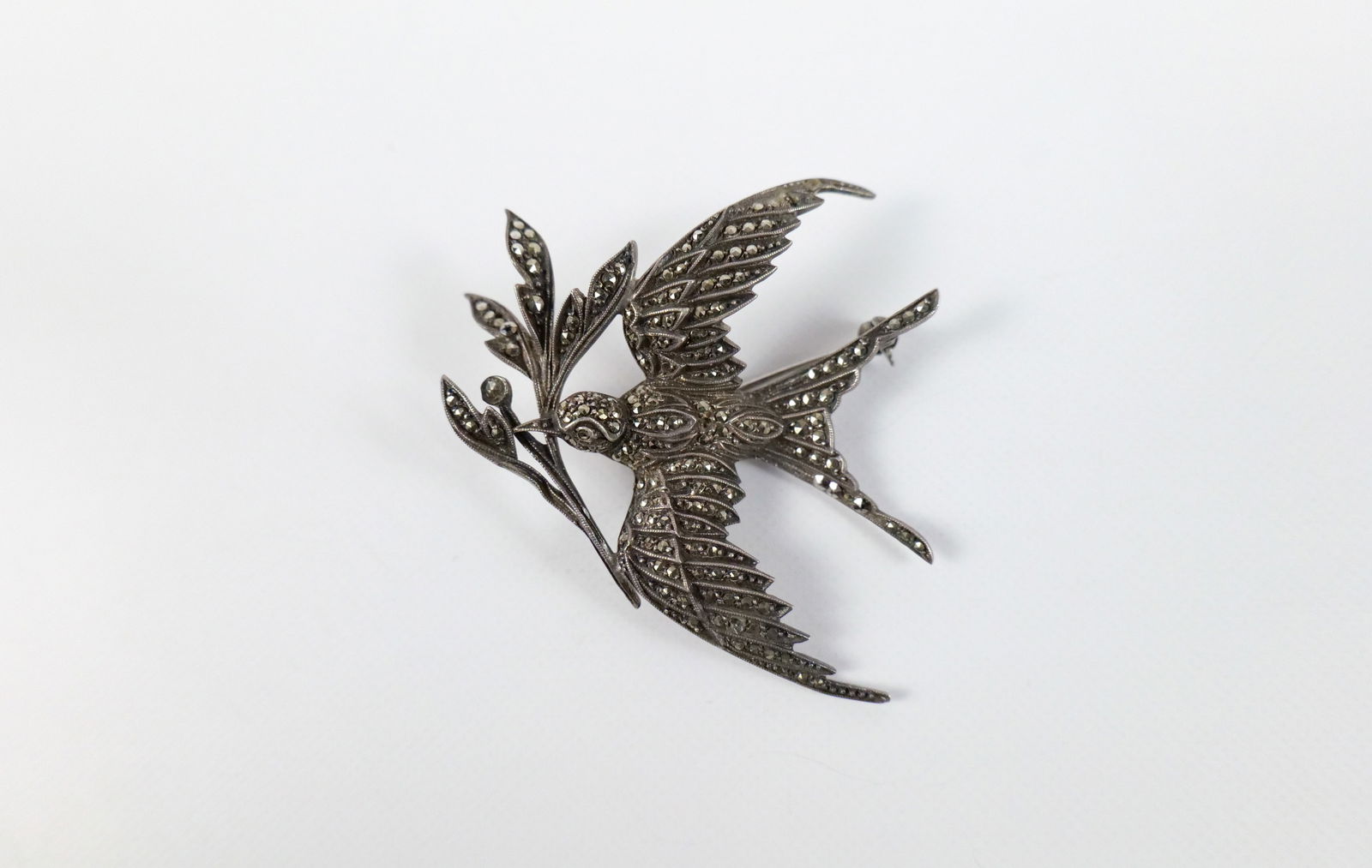 Vintage Sterling and Marcasite Sparrow Brooch: Vintage Sterling and Marcasite Sparrow Brooch. The lot includes a 1.96'' x 1.88'' vintage sterling silver sparrow brooch holding a branch. It is completely studded with marcasites and a hinged bar clo