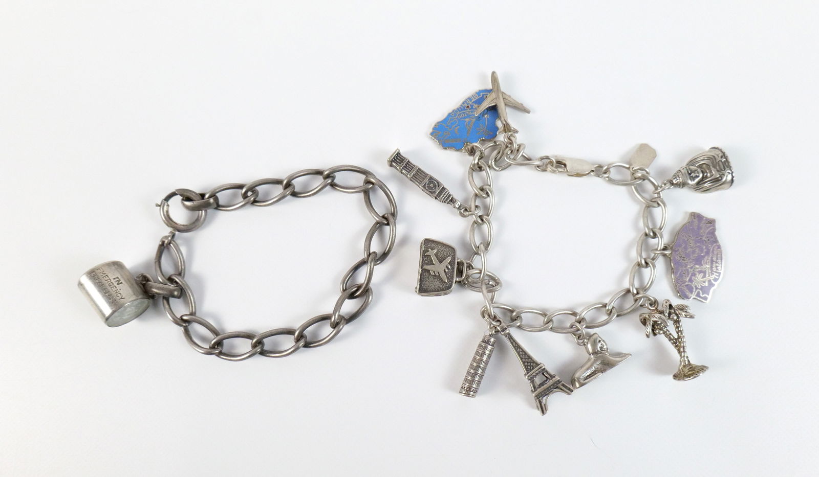 Pair of Vintage Sterling Charm Bracelets: Pair of Vintage Sterling Charm Bracelets. The lot includes a 7''; long oval link chain bracelet from Mango Tango featuring sterling travel themed sterling charms ranging in length from .5'' to 1'' . A