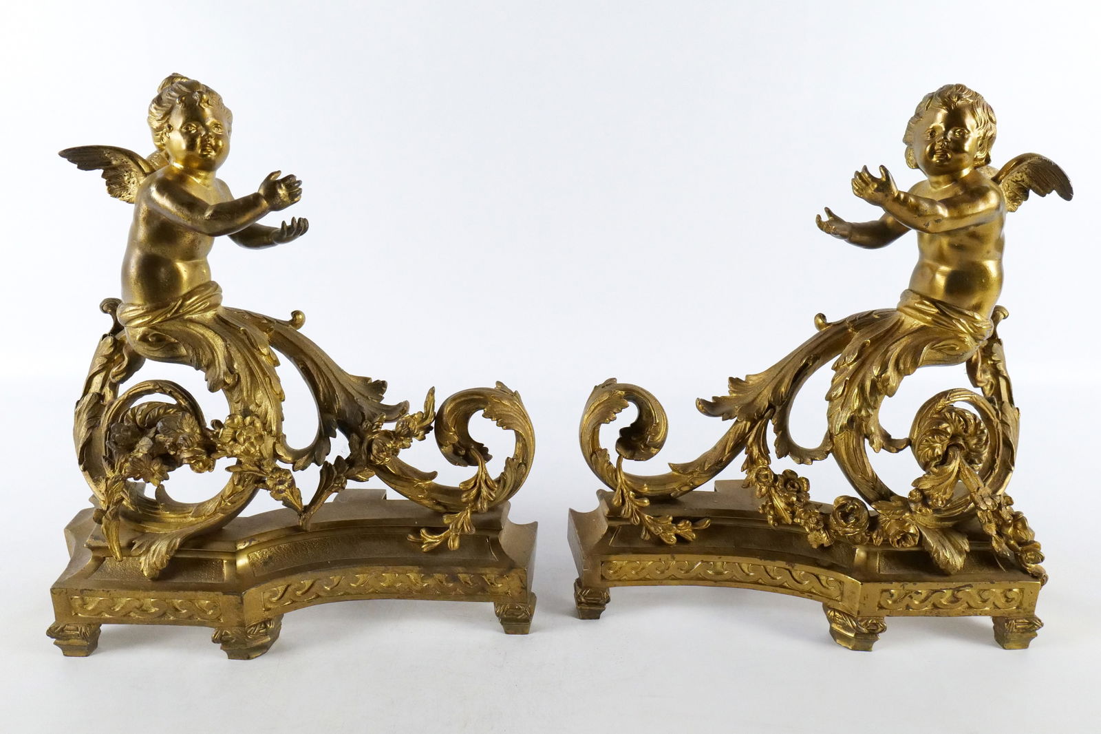 Pair of Gilded Bronze Figural Cherub Ormolu Andirons: Pair of Gilded Bronze Figural Cherub Ormolu Andirons. Marked on back leg PCCP 5. Have floral garland. Measures 12.5" tall x 13" long. All invoices must be paid within 24 hours of the sale. We offer mu