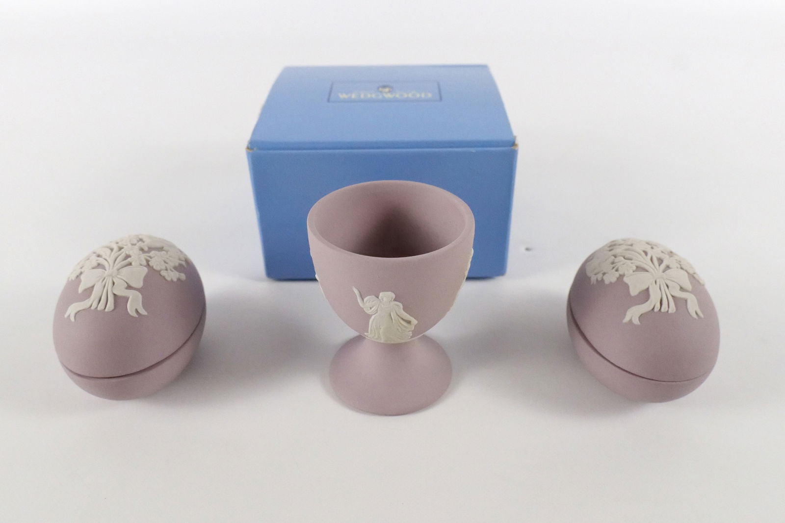 Lot of 3 Wedgwood Lilac and White Jasperware Pieces: Lot of 3 Wedgwood Lilac and White Jasperware Pieces. Including (2) Floral Motif Egg Shaped Trinket Boxes - Collector Society and Egg Cup with Dancing Hours Motif. The Egg Cup comes with the box. Egg C