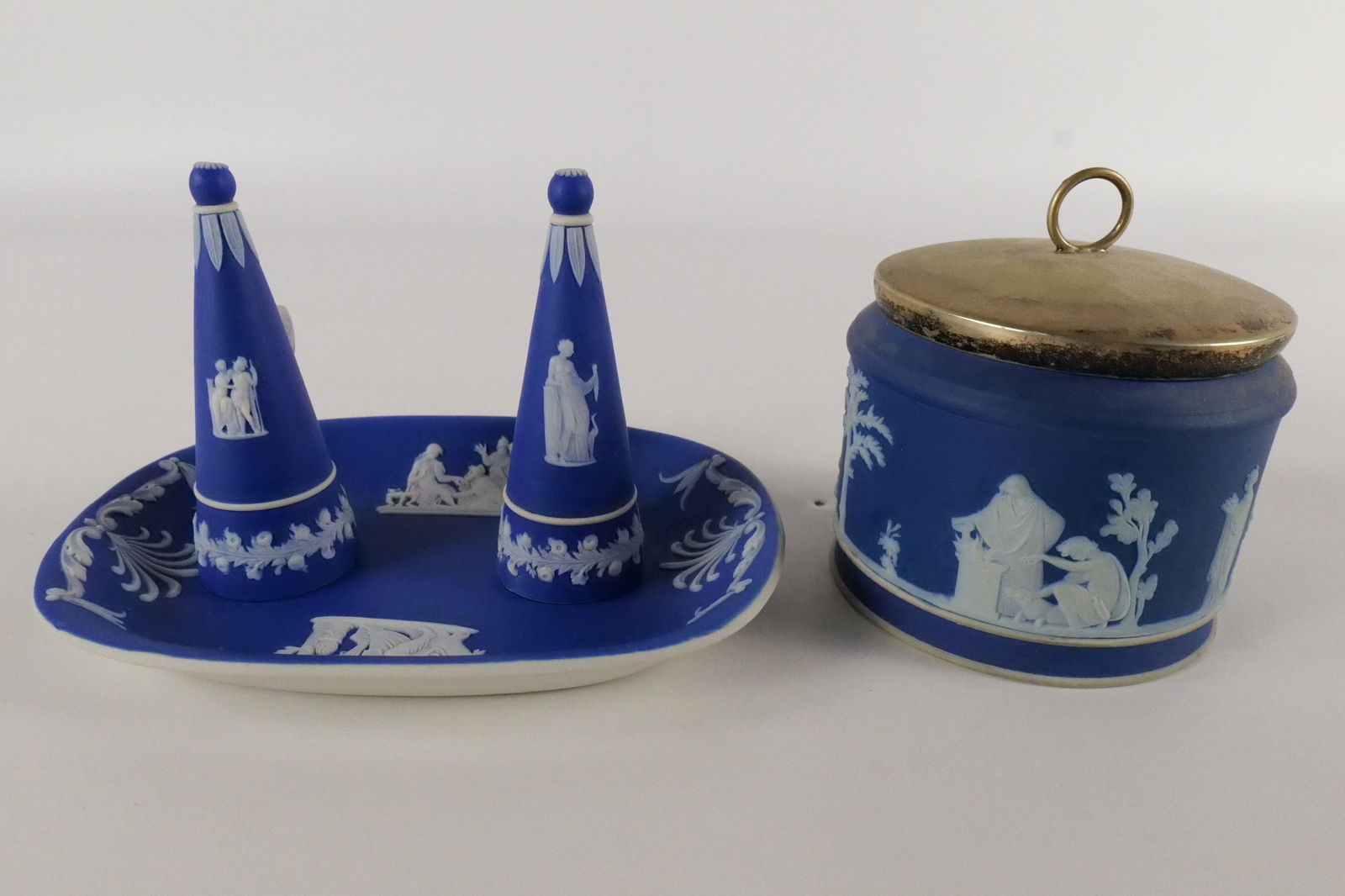 Lot of 2 Wedgwood Cobalt Blue Jasperware Pieces: Lot of 2 Wedgwood Cobalt Blue Jasperware Pieces. Including Candle Snuffer - One has hairline crack and reglued wing and other has been repaired - Depicting Classical Scenes and Jam Pot with Silverplat