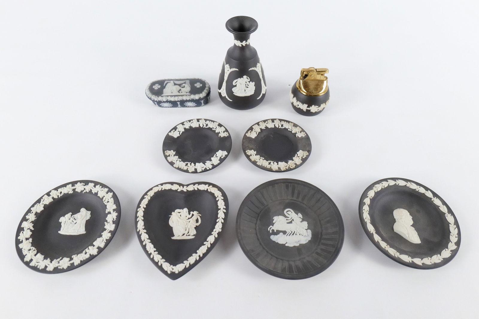 Lot of Wedgwood Black Basalt Jasperware Pieces: Lot of Wedgwood Black Basalt Jasperware Pieces. Including Trinket Dish, Lighter, 2 Ashtrays with Grapevine Scene, Bud Vase, Heart Shaped Trinket, and 3 Small Round Dishes. Tallest measures 5". All inv
