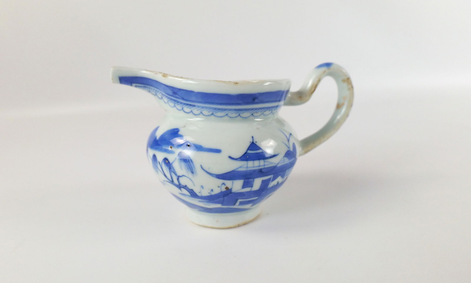 Chinese Export Hand Painted Pitcher/Creamer: Chinese Export Hand Painted Pitcher/Creamer. Blue Asian Scene Design. At least 19th Century or Earlier. Wear to glaze on edges, chipping to spout, missing glaze on handle, staining on the inside and c