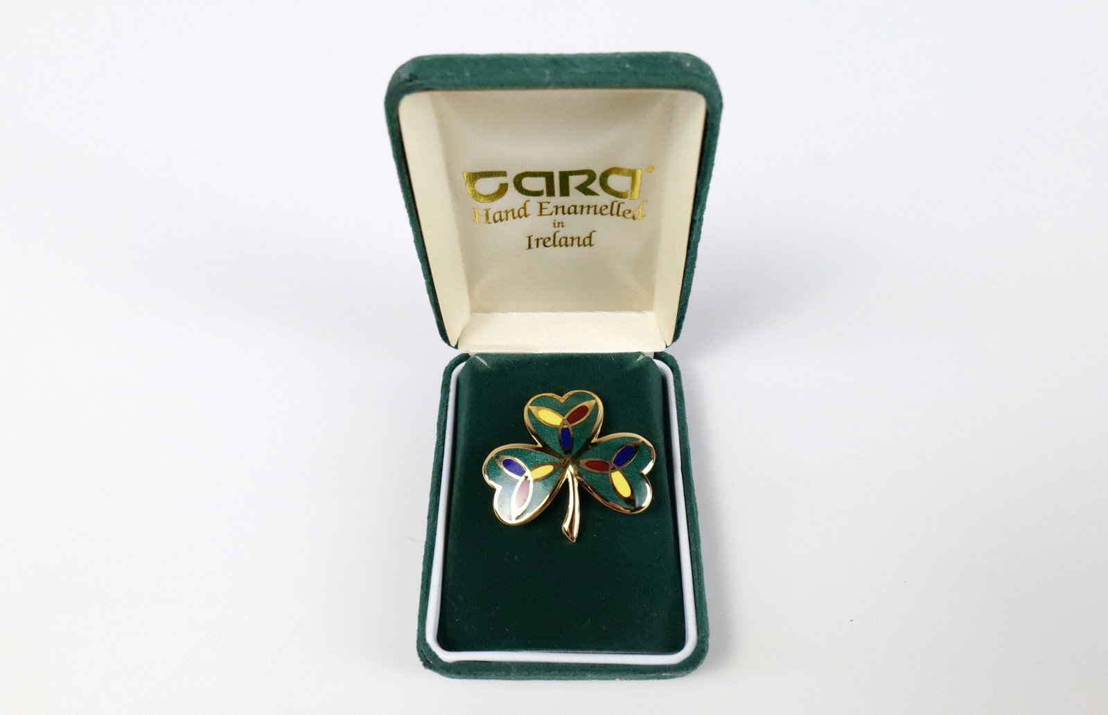 Enameled Celtic Shamrock Brooch by Tara: Enameled Celtic Shamrock Brooch by Tara. The lot includes an Irish enameled Celtic shamrock brooch by Tara featuring enamel in Kelly green, blue, red, and yellow. The brooch has a hinged bar closure a