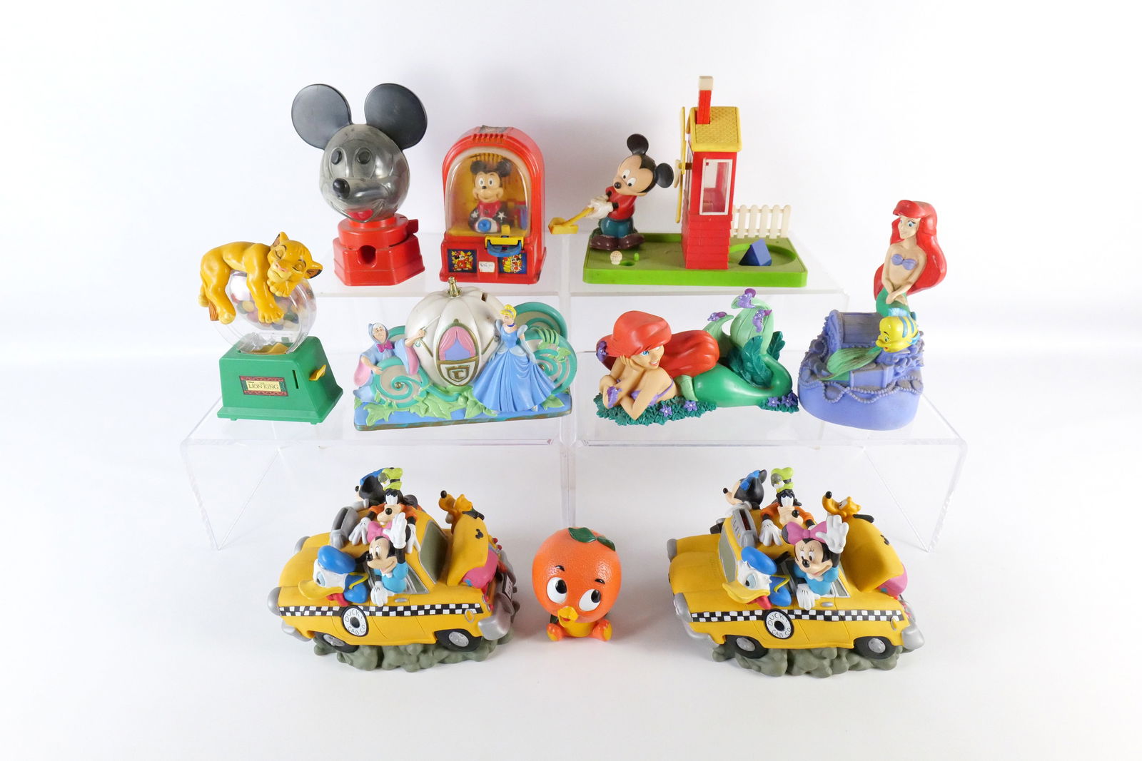Lot of Disney Plastic Banks: Lot of Disney Plastic Banks. Including 2 Fab Five Taxi Cabs, Cinderella Coach, Simba Gumball Bank, Ariel Bank, Mickey Golfing Bank, Florida Orange Bird, Buddy L Mickey Fortune Teller Bank, and Vintage