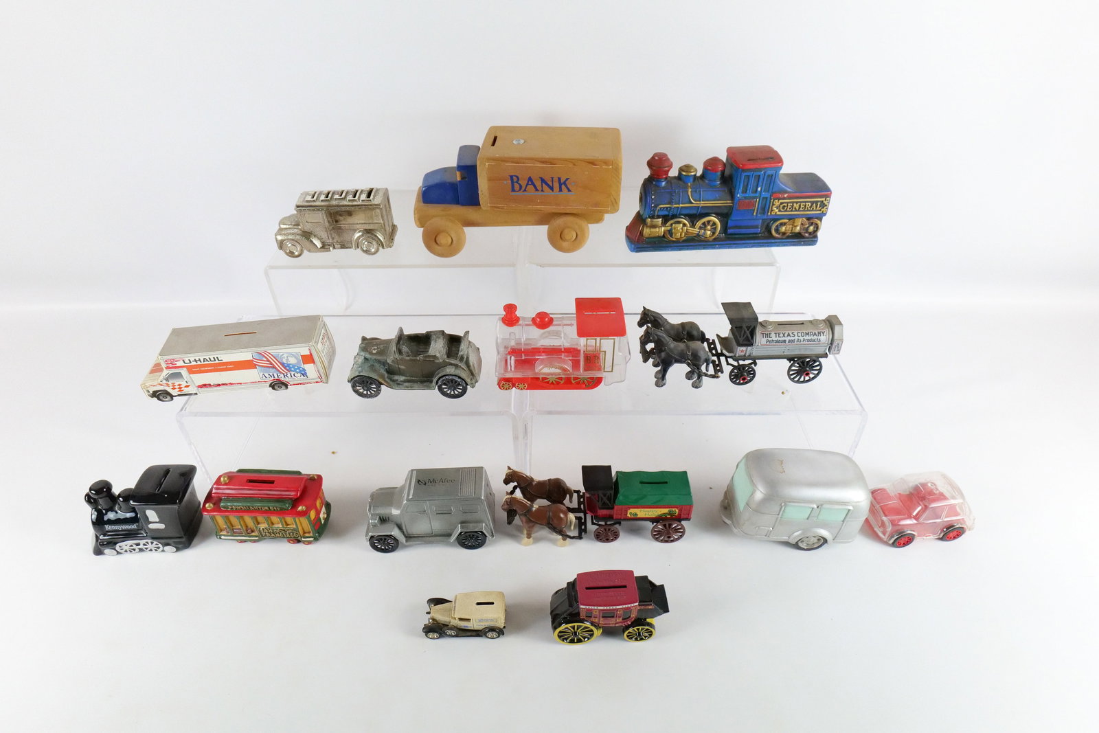 Lot of Assorted Material Vehicle Banks: Lot of Assorted Material Vehicle Banks. Including Metal, Wooden, Plastic and Cardboard. One has corrosion. Wells Fargo, U-Haul, The General Train, Ertl, San Francisco Trolley Car, and More. One is mis