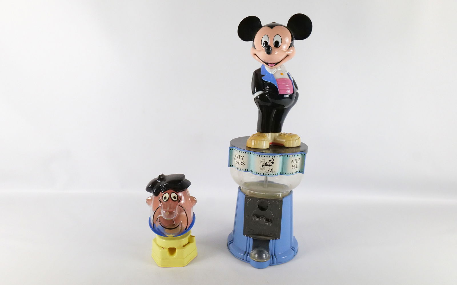 Lot of 2 Vintage Gumball Machines: Lot of 2 Vintage Gumball Machines. Including Fred Flintstone Plastic 1968 Hasbro - Nose has some damage and 60 Years with Mickey Mouse Dated 1988 - Metal Base with Plastic Top and Figure. Tallest meas