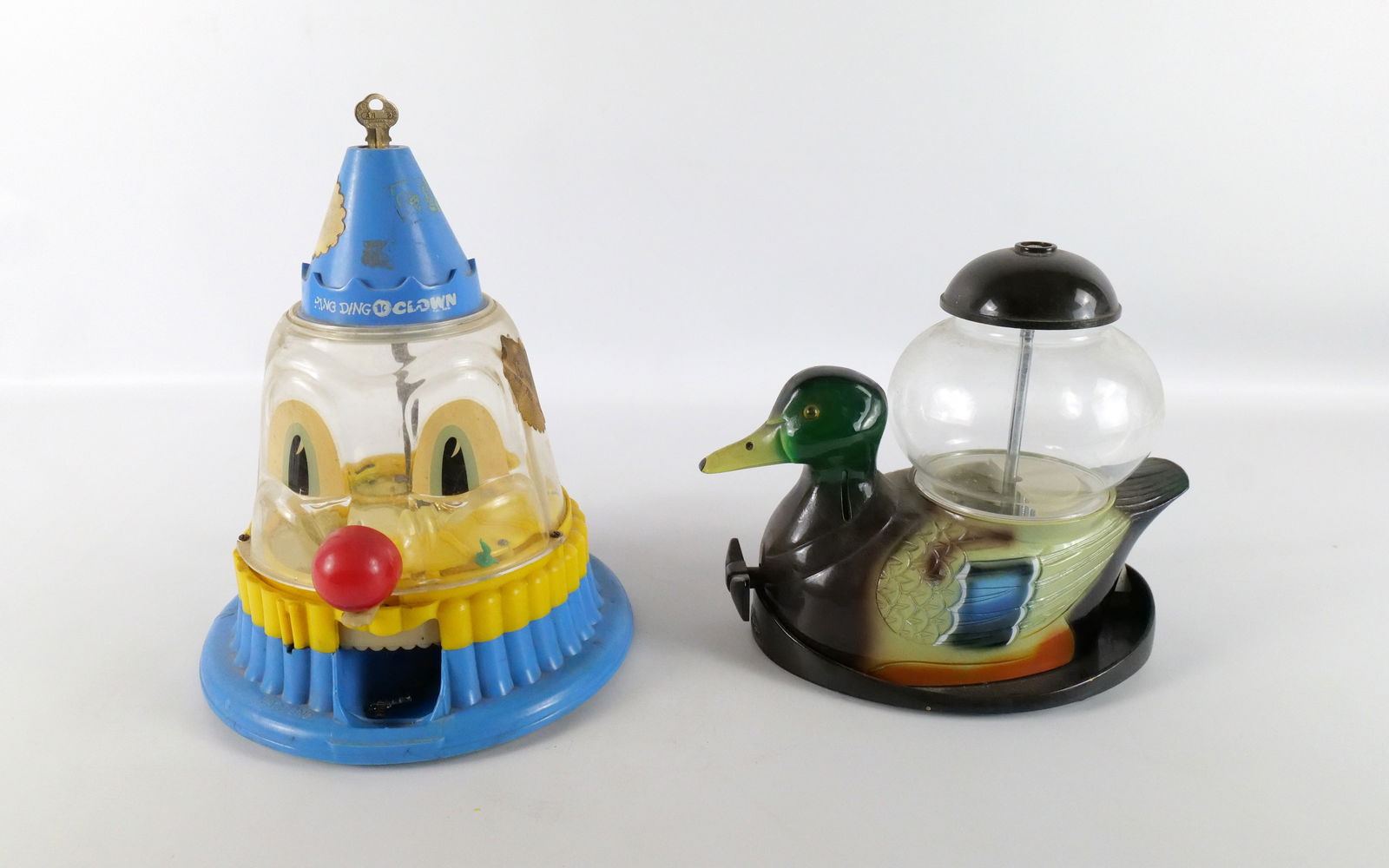 Lot of 2 Gumball and Charm Machines: Lot of 2 Gumball and Charm Machines. Including Ring Ding the Clown Charm Machine - Comes with some charms inside - Some wear, scratching, and discoloration and Metal and Glass Decoy Duck Gumball