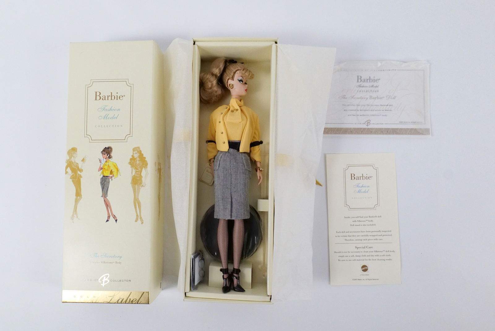 The Secretary Silkstone Gold Label Barbie Doll: The Secretary Silkstone Gold Label Barbie Doll - Fashion Model Collection. New in Box. Her face does have a green smudge from her earring. I tried to get it off with water and towel but it is still on