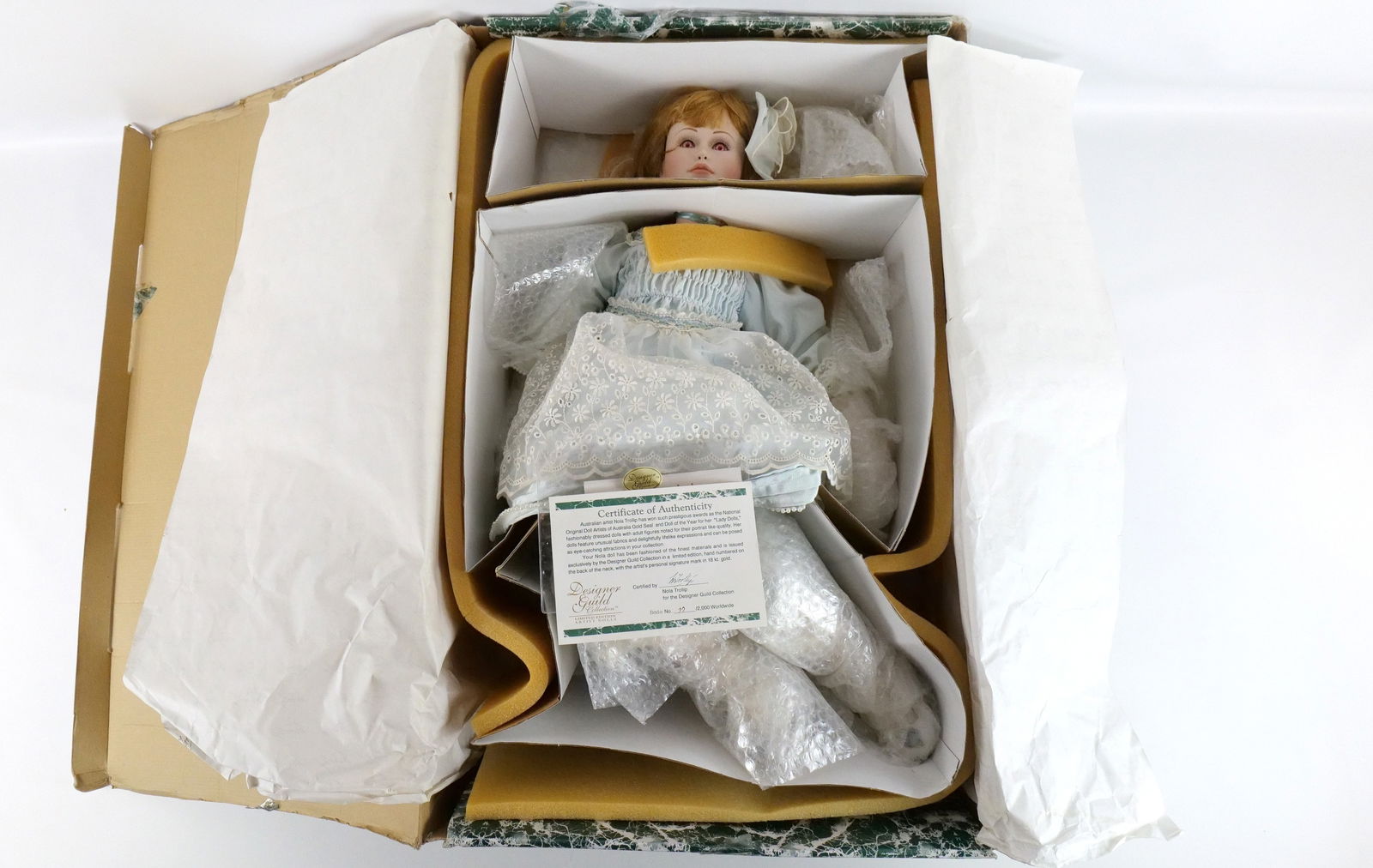 Designer Guild Bridie Artist Porcelain Doll: Designer Guild Bridie Artist Porcelain Doll. Made by Nola Trollip - Seated. She appears to have been taken out of the box. Comes with COA. Some discoloration on her white on her dress. Limited Edition