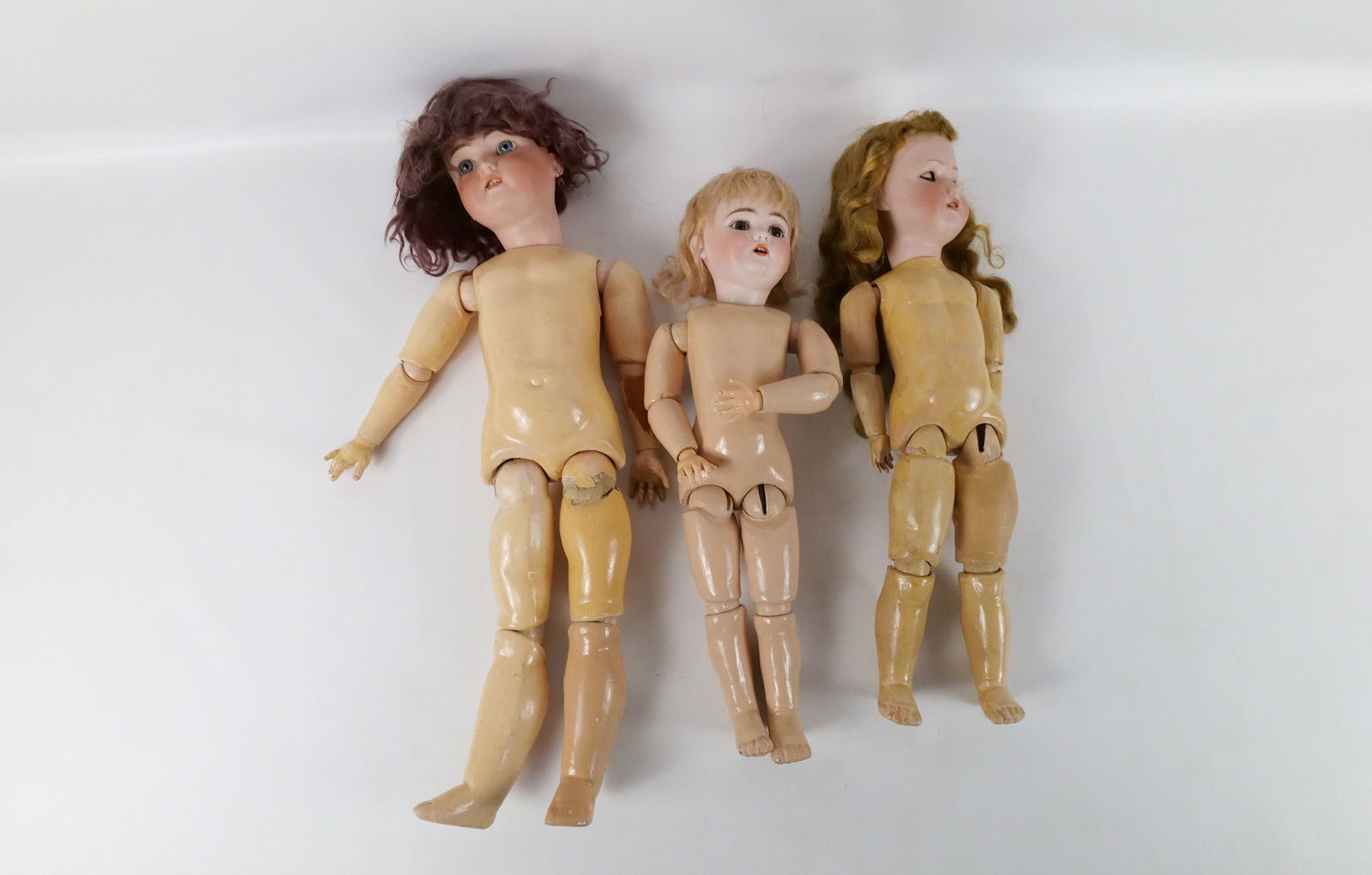 Lot of 3 Antique German Dolls: Lot of 3 Antique German Dolls. All have bisque heads with composition bodies. One has sleepy eyes. One doll has heavier wear to her body. Largest measures 25.5" long. All invoices must be paid within