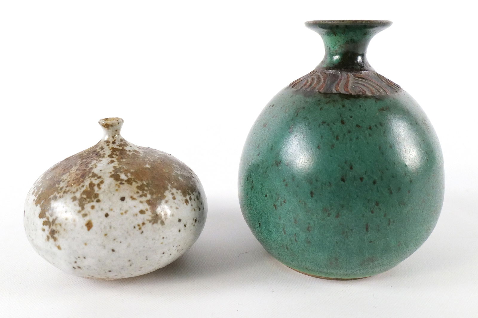 Lot of 2 Art Pottery Bud Vases/Fragrance/Oil Bottles: Lot of 2 Art Pottery Bud Vases/Fragrance/Oil Bottles. Tall green is artist signed on bottom. Small unsigned vase has chipping to the top rim. Largest measures 5" tall. All invoices must be paid