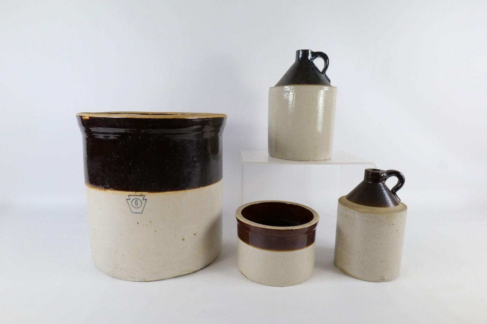 Lot of 4 Antique Stoneware Crocks and Whiskey Jugs: Lot of 4 Antique Two-Tone Stoneware Crocks and Whiskey Jugs. Including 6 Gallon Crock, Smaller Crock, and 2 Jugs. The jugs have chipping on the top rim and chipping on the middle rims. The 6 gallon cr
