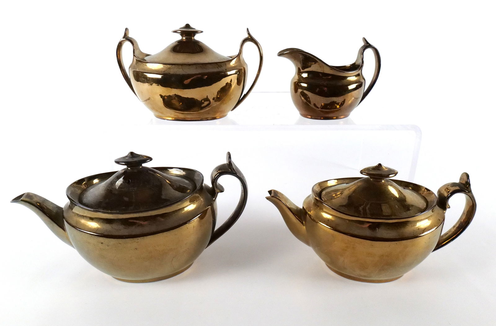 Lot of Gold Lusterware: Lot of Gold Lusterware. Including 2 Teapots, Creamer and Sugar. One is as-is. Largest measures 5.75" tall x 10.5" wide. All invoices must be paid within 24 hours of the sale. We offer multiple shippin