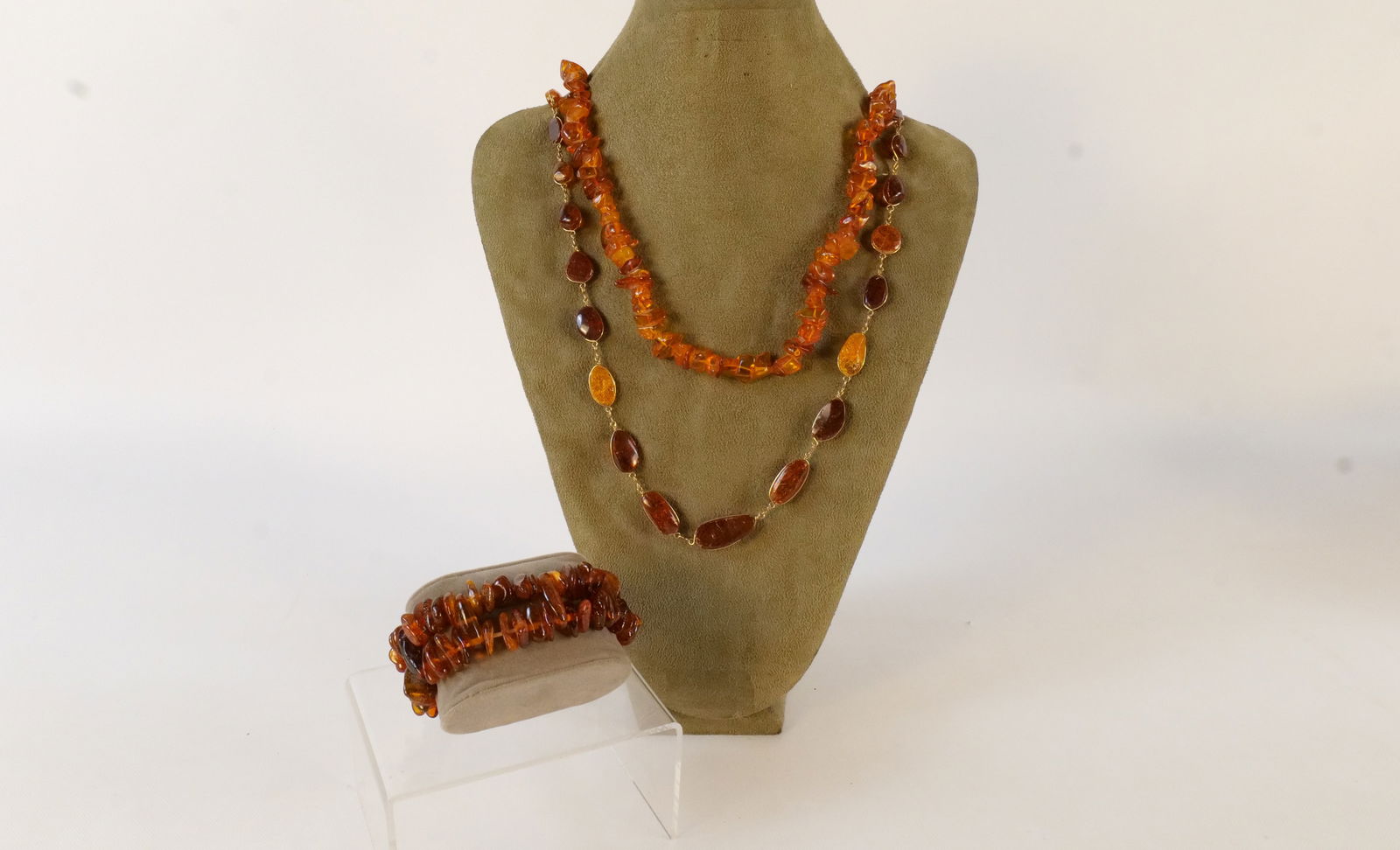 Lot of Amber Jewelry: Lot of Amber Jewelry. Including Beaded Necklace, 28" Bezel Set Gold Tone Necklace, and Double Strand Beaded Stretch Bracelet. All invoices must be paid within 24 hours of the sale. We offer multiple s