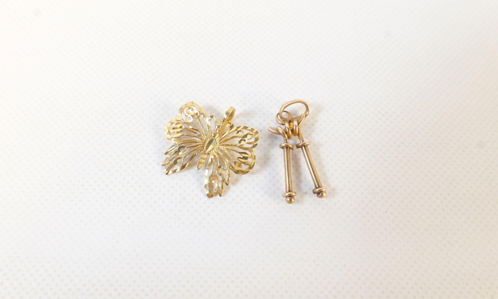 Lot of 14k Gold Jewelry: Lot of 14k Gold Jewelry. Weighs approx. 1.8 grams. Including Filagree Butterfly Pendant and Charm with Ski Poles. All invoices must be paid within 24 hours of the sale. We offer multiple shipping opti