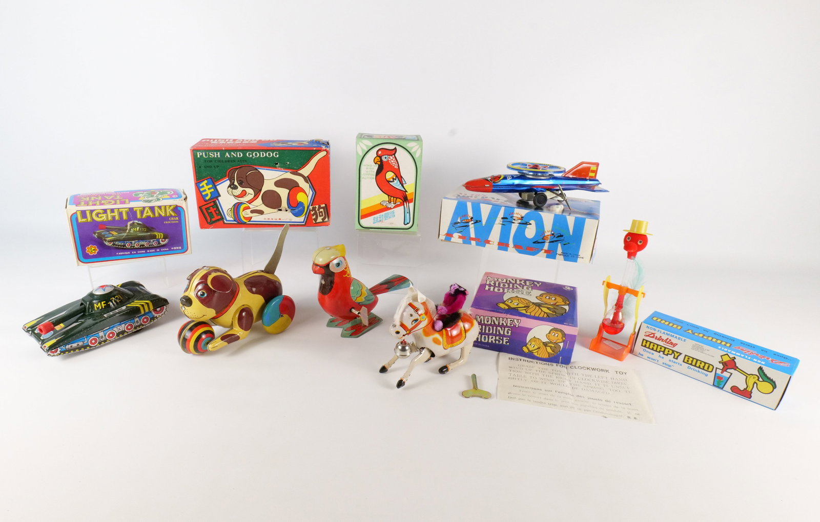Lot of Mechanical Toys in Boxes: Lot of Mechanical Toys in Boxes. Including Push and Go Dog, Clockwork Avion Aircraft, Drinking Happy Bird, Key Wind Monkey Riding Horse, Wind Up Jumping Parrot, and Friction Light Tank. All invoices m