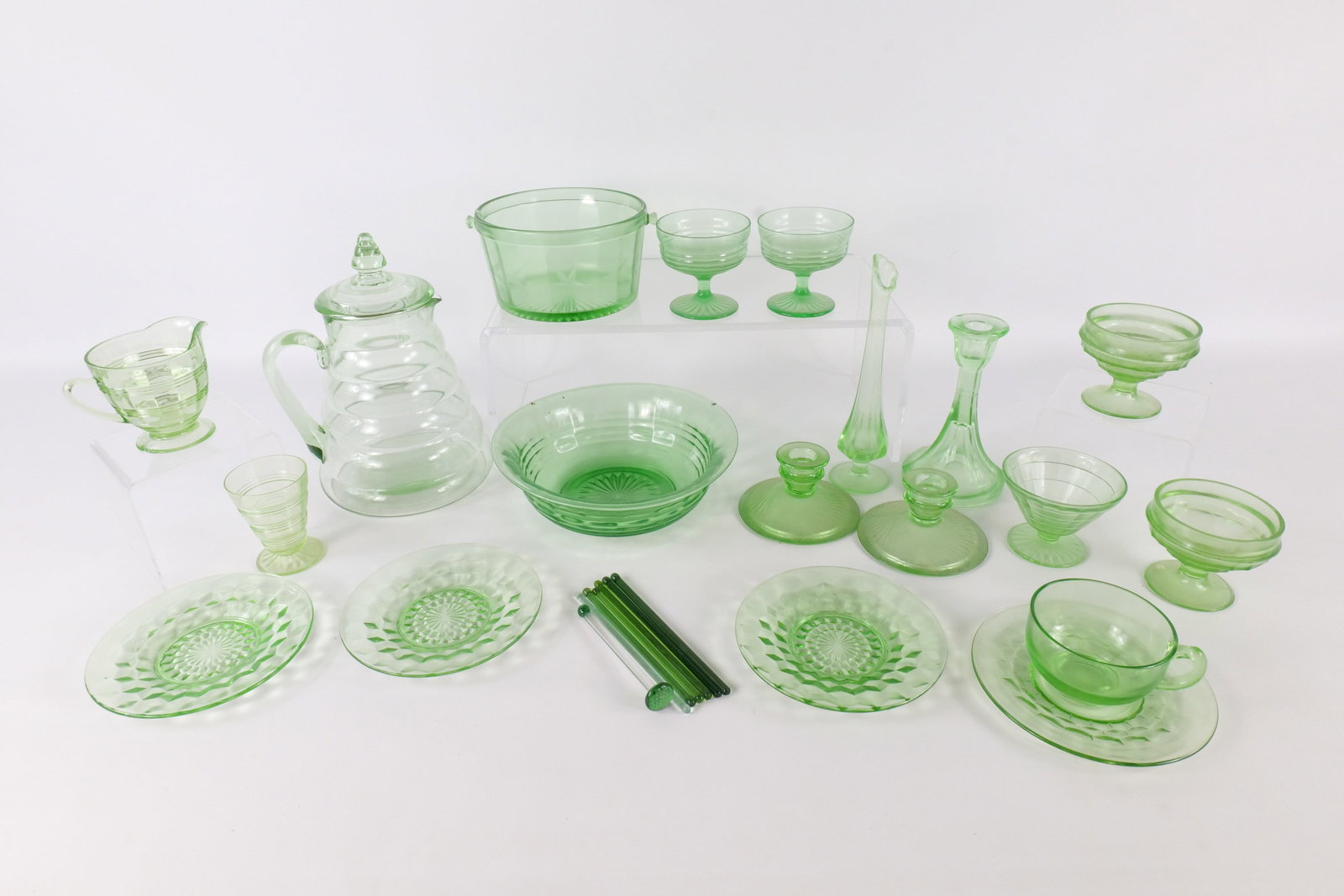 Lot of Green Depression Glass: Lot of Green Depression Glass. Including Bud Vase, Serving Bowl, Ice Bowl, Sherbert Cups, Saucers, Candlestick Holders, Pitcher and More. Mixed Patterns. Tallest measures 10". Some chipping on Various