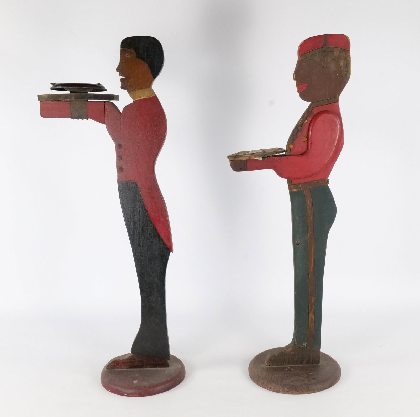 Pair of Vintage Mid-Century Wooden Silent Butler/Bellhop Stands: Pair of Vintage Mid-Century Wooden Silent Butler/Bellhop Stands. Some natural wood splitting. Some paint loss. Features original metal tacks/buttons on the uniforms. One has integrated metal to hold a