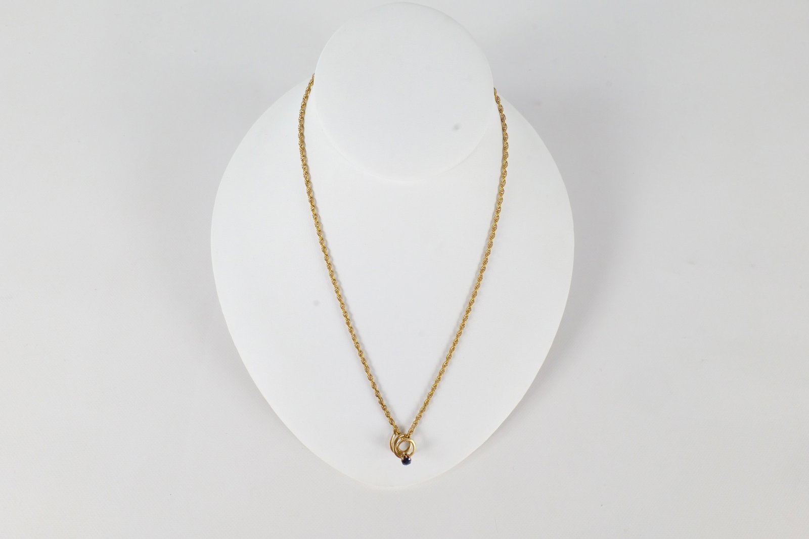 14K Yellow Gold Jewelry: Two pieces of 14 K yellow gold jewelry including a rope chain that is missing the hook for the clasp and a Lapel pin in a circular pattern with a small sapphire or bluestone. The rope chain measures a