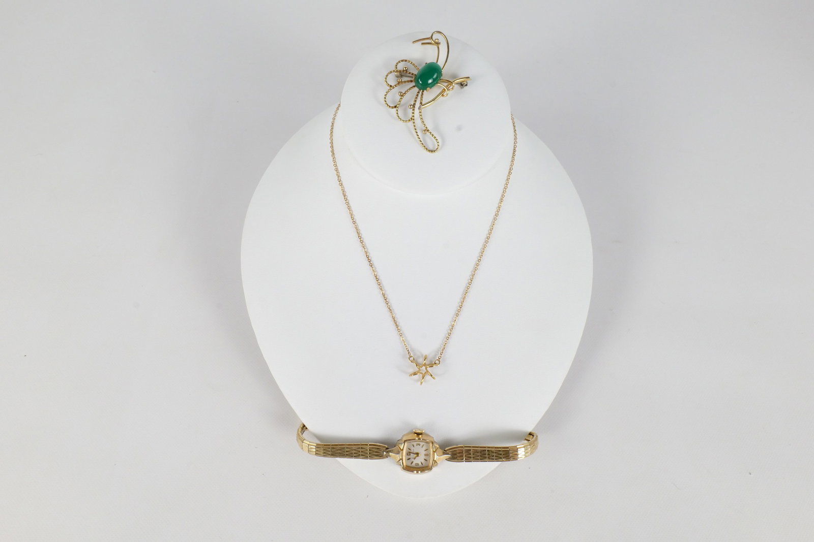 Lot of Gold Filled Jewelry: Lot of gold filled jewelry including a Krementz 's bird pin with cabochon stone, a gold filled Bulova watch, and a gold filled chain with a swirl floral type pendant. The chain measures approx. 15" an