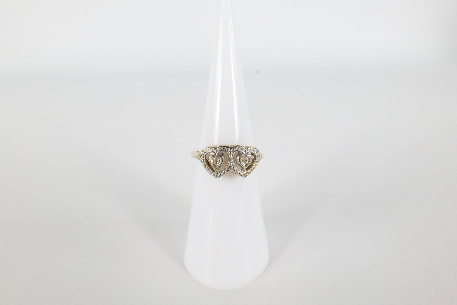 10K Gold Ladies Ring: A 14 K yellow and white gold ladies ring with two hearts along the front. Has one small diamond chip in one of the hearts the other diamond chip is missing. Is marked on the inside of the band. Size