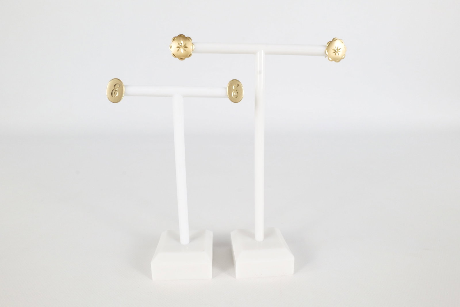 2 Pairs 14K Earrings: Two pairs of 14 K yellow gold stud earrings. The first pair is an Oval shape with an E etched in the center and is marked on the back of the earring. The second pair has a sunburst pattern etched in