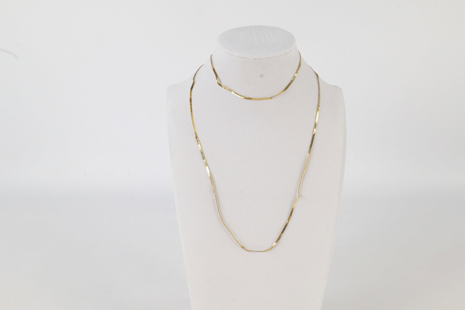 14K Herringbone Necklace: A 14 K yellow gold herring bone necklace. Marked on the clasp. Has kinks throughout. Measures approximately 29". All invoices must be paid within 24 hours of the sale. We offer multiple shipping optio