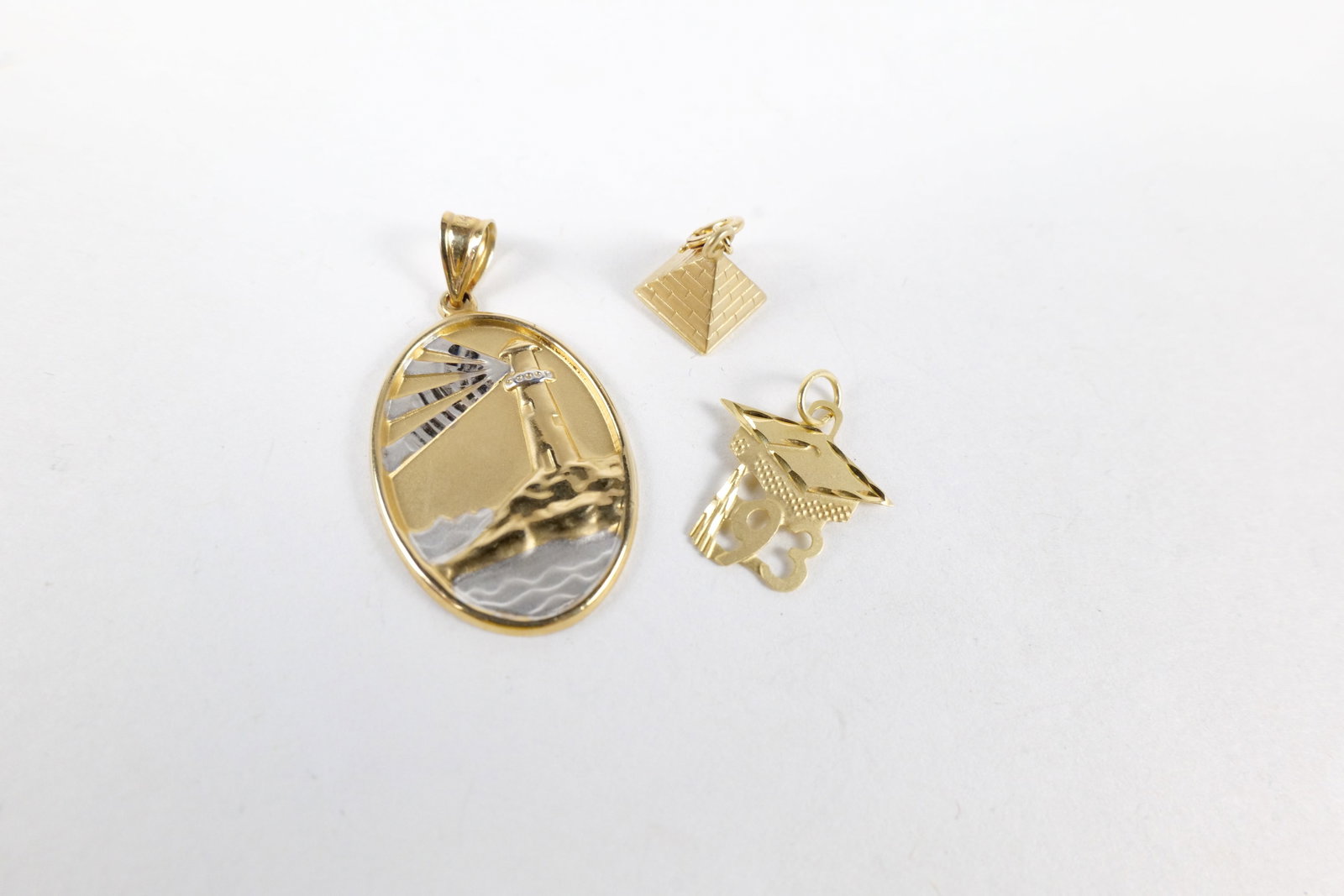 Lot of 3 14k Gold Charms: Lot of 3 14k Gold Charms - Pyramid, Lighthouse (White and Yellow Gold), and '93 Graduation Charm - All Marked. Weighs 2.9 grams. Largest measures 1.25" long. All invoices must be paid within 24 hours