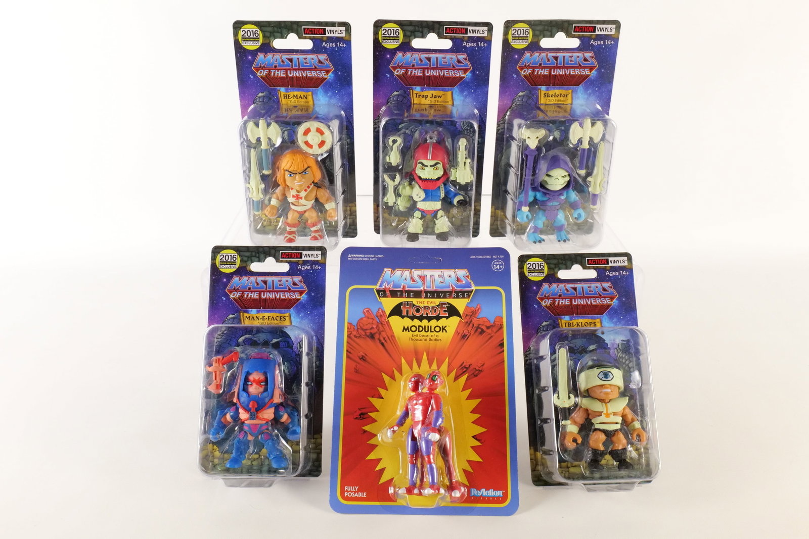 Lot of Masters of the Universe Figures: Lot of Masters of the Universe Figures. Including Action Vinyls GID Edition - (Man-E-Faces, Tri-Klops, Skeletor, He-Man, and Trap Jaw) and ReAction Super 7 Evil Horde Modulok Figure. All new in packag