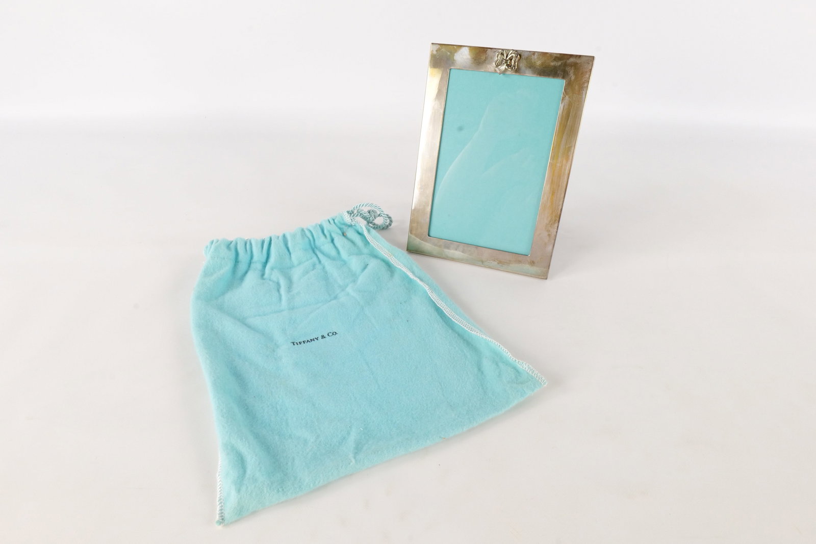 Tiffany & Co. Sterling Photo Frame: Tiffany & Co. Sterling Photo Frame. Has bow on top. Marked on Bottom. Measures 7" tall x 5" wide. Comes with bag. Has some scratches and has a little tarnish. All invoices must be paid within 24 hours