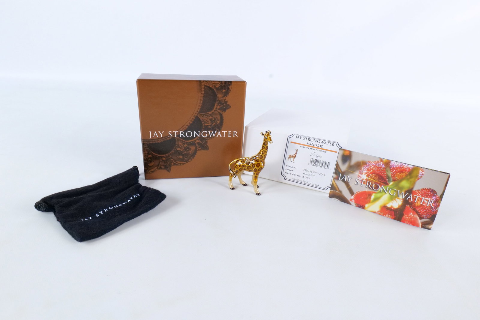 Jay Strongwater Twiga Giraffe Mini Figurine: Jay Strongwater "Twiga" giraffe mini figurine. From the Jungle collection. Color amber. Style # ADH1743274. Golden brown enameled giraffe with amber spots is accented with corresponding rhinestones/cr