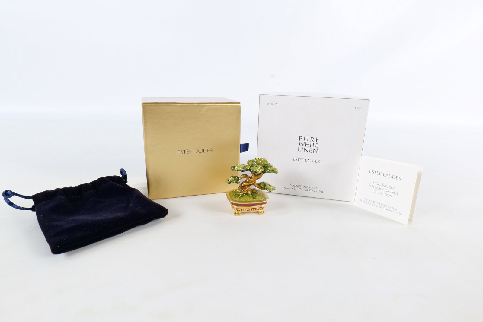 Estee Lauder/Jay Strongwater Magnificent Bonsai Perfume Compact: 2007 Estee Lauder Magnificent Bonsai Pure White Linen compact for solid perfume. Designed by Jay Strongwater. Green and brown enamel bonsai tree sits atop a gold tone planter. Has corresponding rhines
