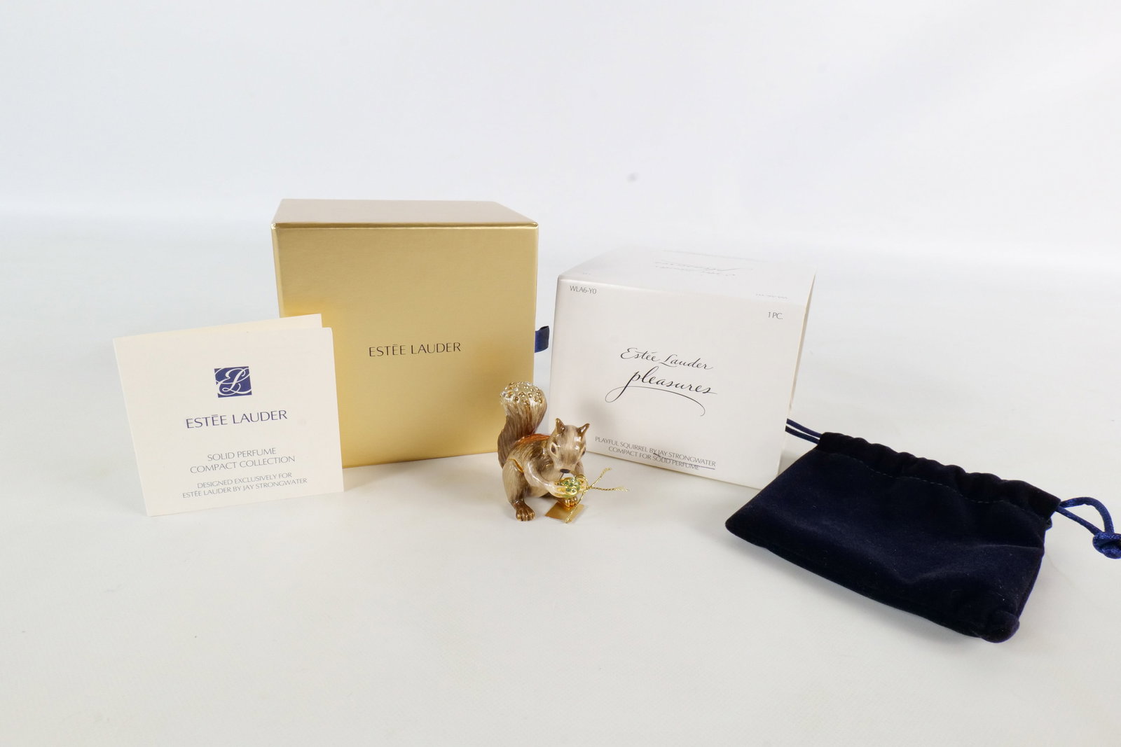 Estee Lauder/Jay Strongwater Playful Squirrel Perfume Compact: 2010 Estee Lauder Playful Squirrel Pleasures compact for solid perfume. Gray and amber enameled squirrel with a gold tone acorn. Has corresponding rhinestones on the acorn and tail. Unused. Comes with