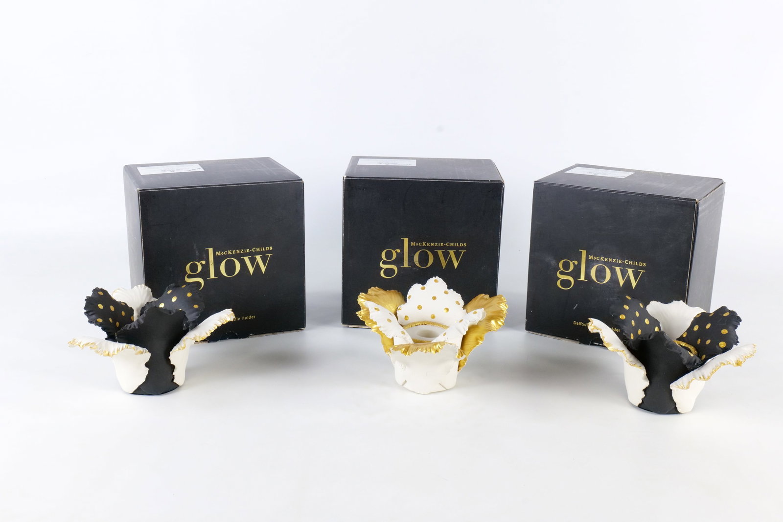 3 MacKenzie Child's Glow Candle Holders: Lot of 3 MacKenzie Child's Glow daffodil candle holders. 2 in black and one in gold. All come with original box. Measures approx. 3 1/2" tall x 5 1/2" wide. All invoices must be paid within 24 hours o