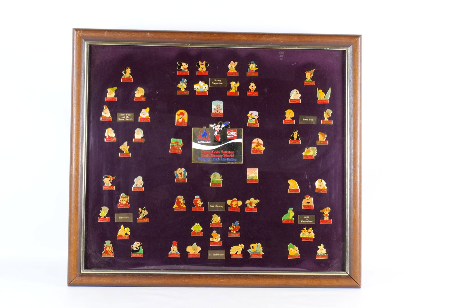 Walt Disney/Coca Cola Framed Disney Pin Set: Walt Disney/Coca Cola Framed Disney Pin Set. Entitled "Coca Cola Salutes Walt Disney World Happy 15th Birthday". Features sixty pins. Dated 1986. Frame measures 22 1/2 inches tall by 25 1/2 inches wid