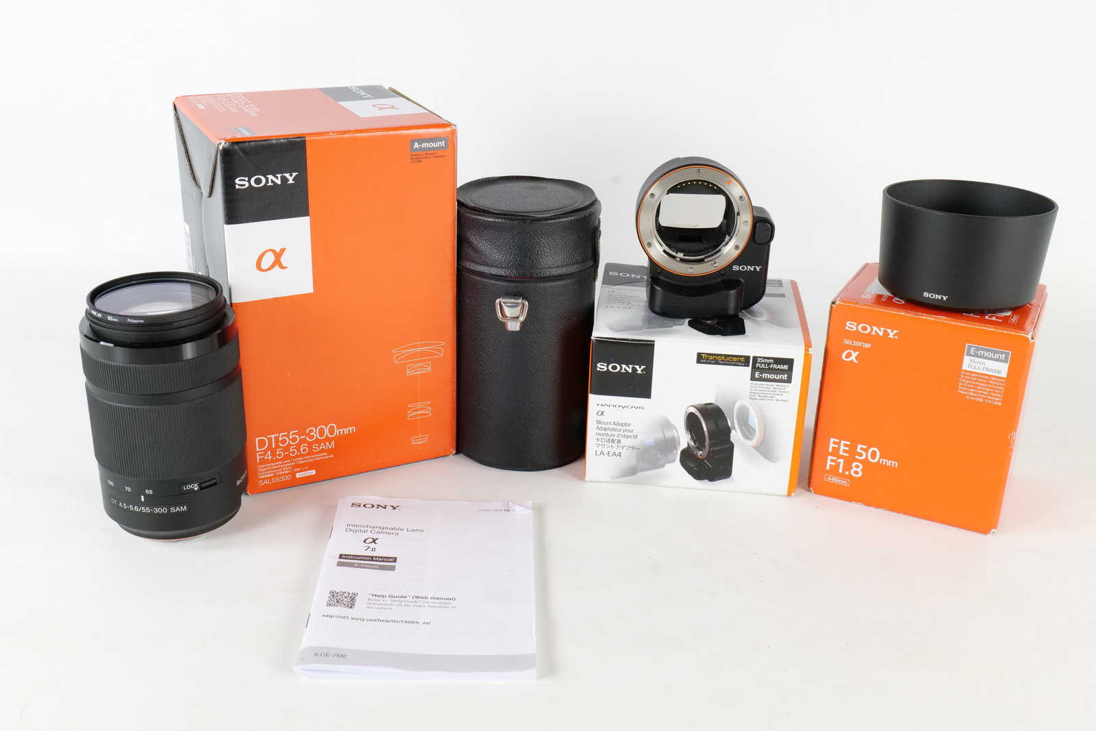 A Collection of Sony Camera Equipment: This Sony collection features a DT 55-300mm lens, an LA-EA4 mount adapter, and various retail packaging. The set includes a Hoya UV filter and a cylindrical hard-shell lens case. "All invoices must
