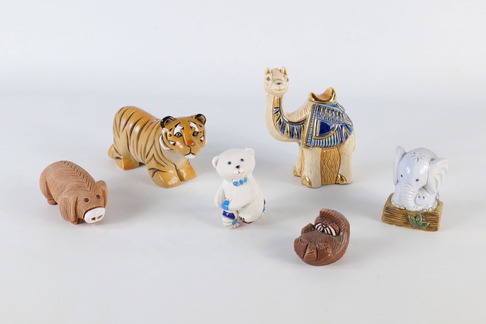A Collection of Artesnia Rinconada Figurines: A collection of hand-carved ceramic animal figurines by Artesania Rinconada. These pieces feature various animals with textured stoneware finishes, colorful glazes, and metallic accents. Including, lo