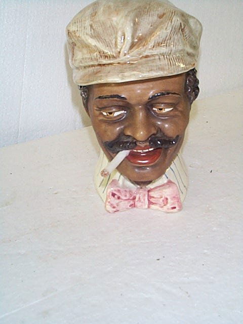 Porcelain figural tobacco jar head depicting a bla: Porcelain figural tobacco jar head depicting a black man with a mustache smoking a cigarette. Measures 7.5" tall. Buyer to pay $20.00 shipping and handling, all items to be sent USPS Priority Mail wit