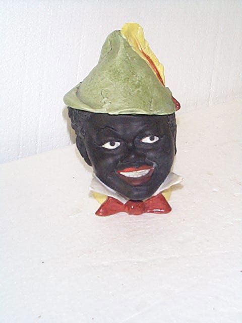 Bisque figural tobacco jar head depicting a black: Bisque figural tobacco jar head depicting a black man wearing a hat with a feather in it. Measures 6.5" tall. Buyer to pay $20.00 shipping and handling, all items to be sent USPS Priority Mail with De